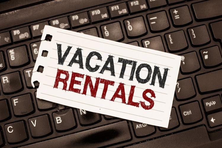 Piece of paper that reads, "Vacation Rentals" atop keyboard.