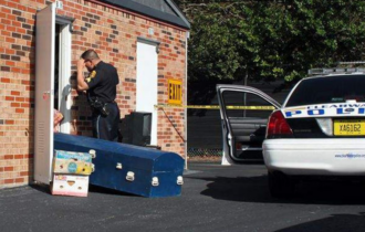 Police officer removing casket from self-storage unit.