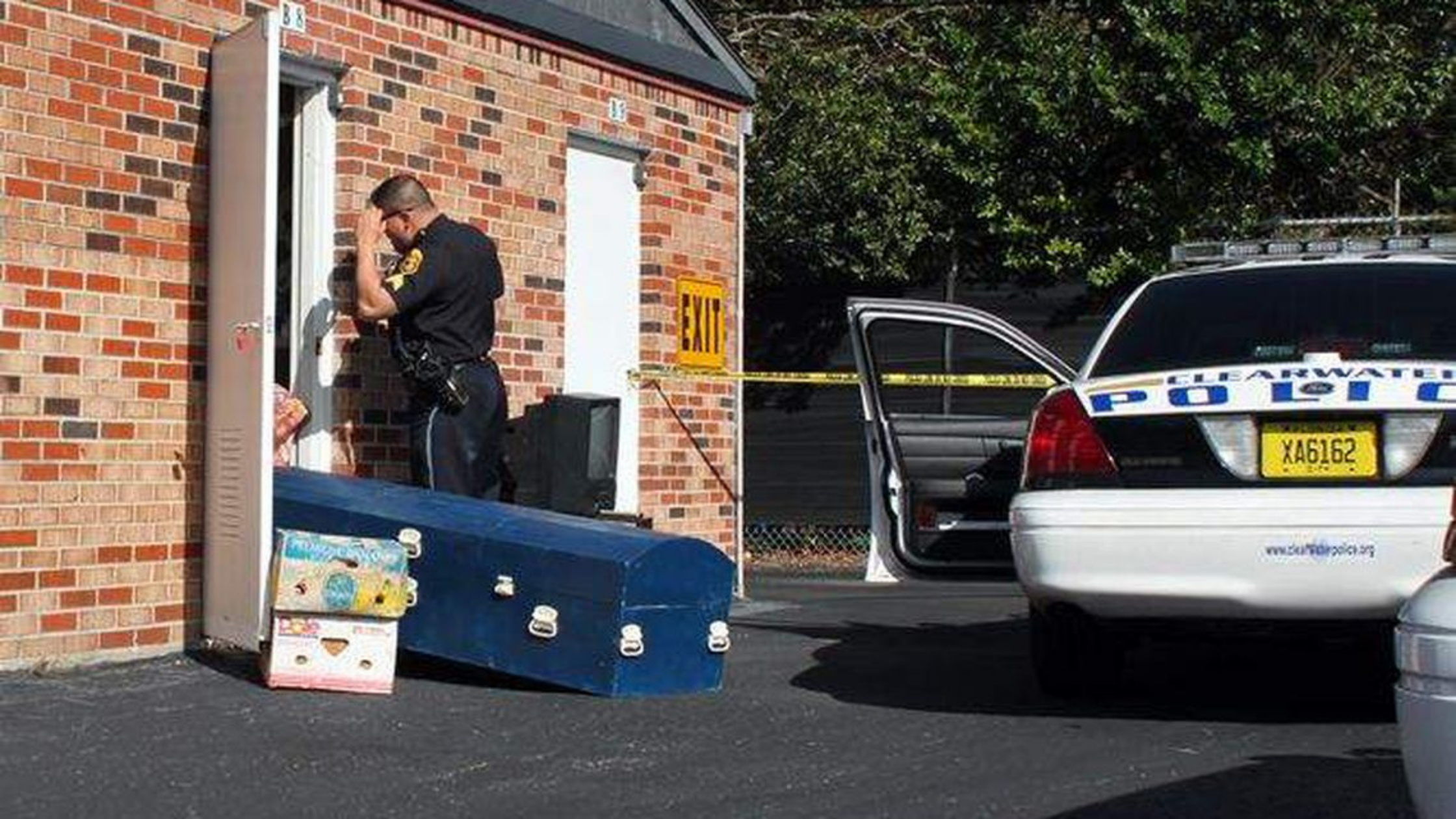 Police officer removing casket from self-storage unit.