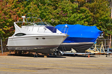 Uncovered boat next to boat covered with tarp.