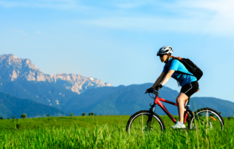 Cyclist riding bike with mountains in background.