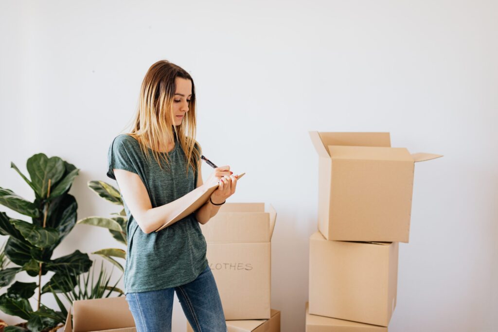 Woman taking note while packing boxes