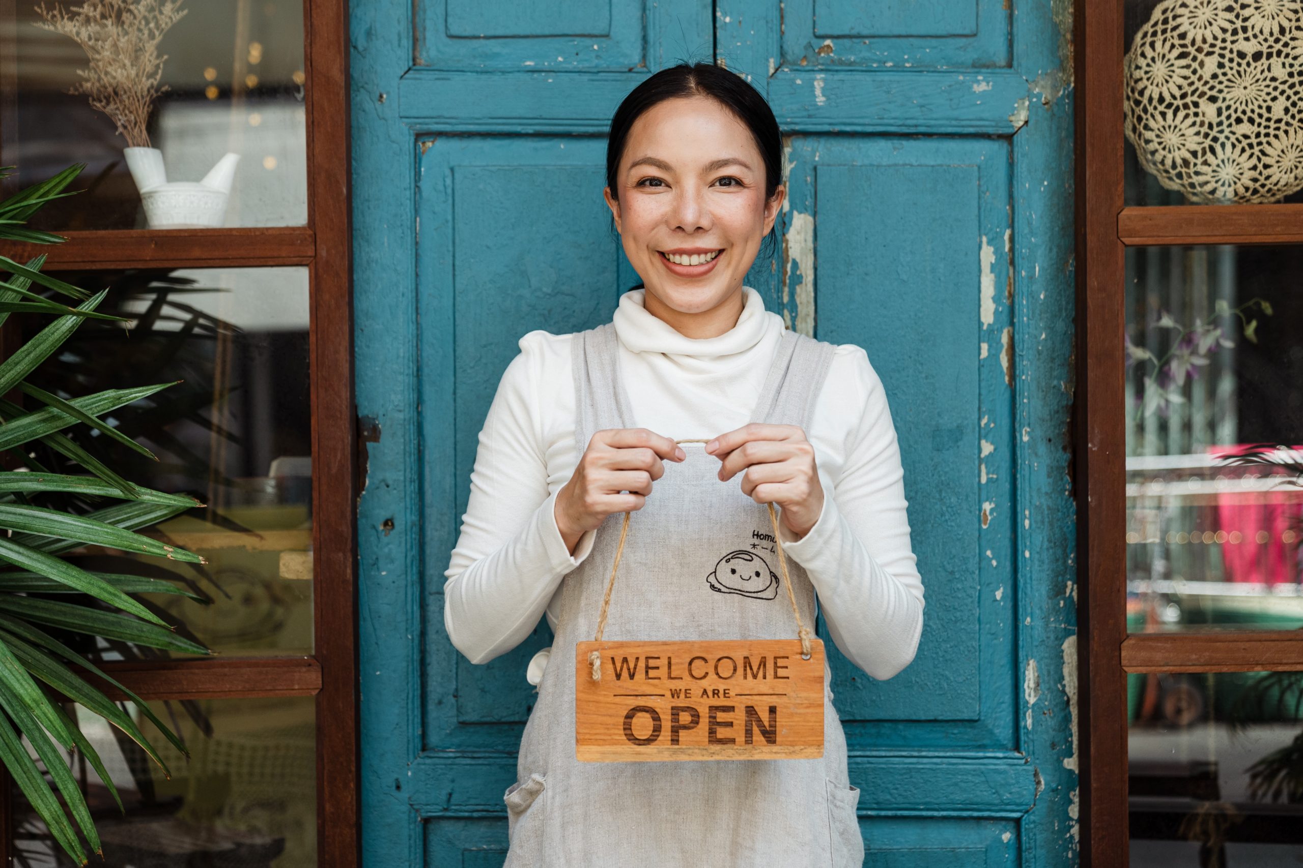 Woman holding welcome/open sign for her business.