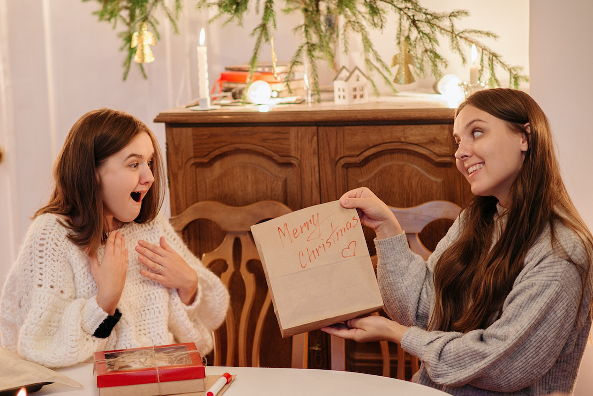 Girl giving a Christmas present to another girl.
