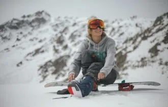 Person sitting on snowboard on winter slope.